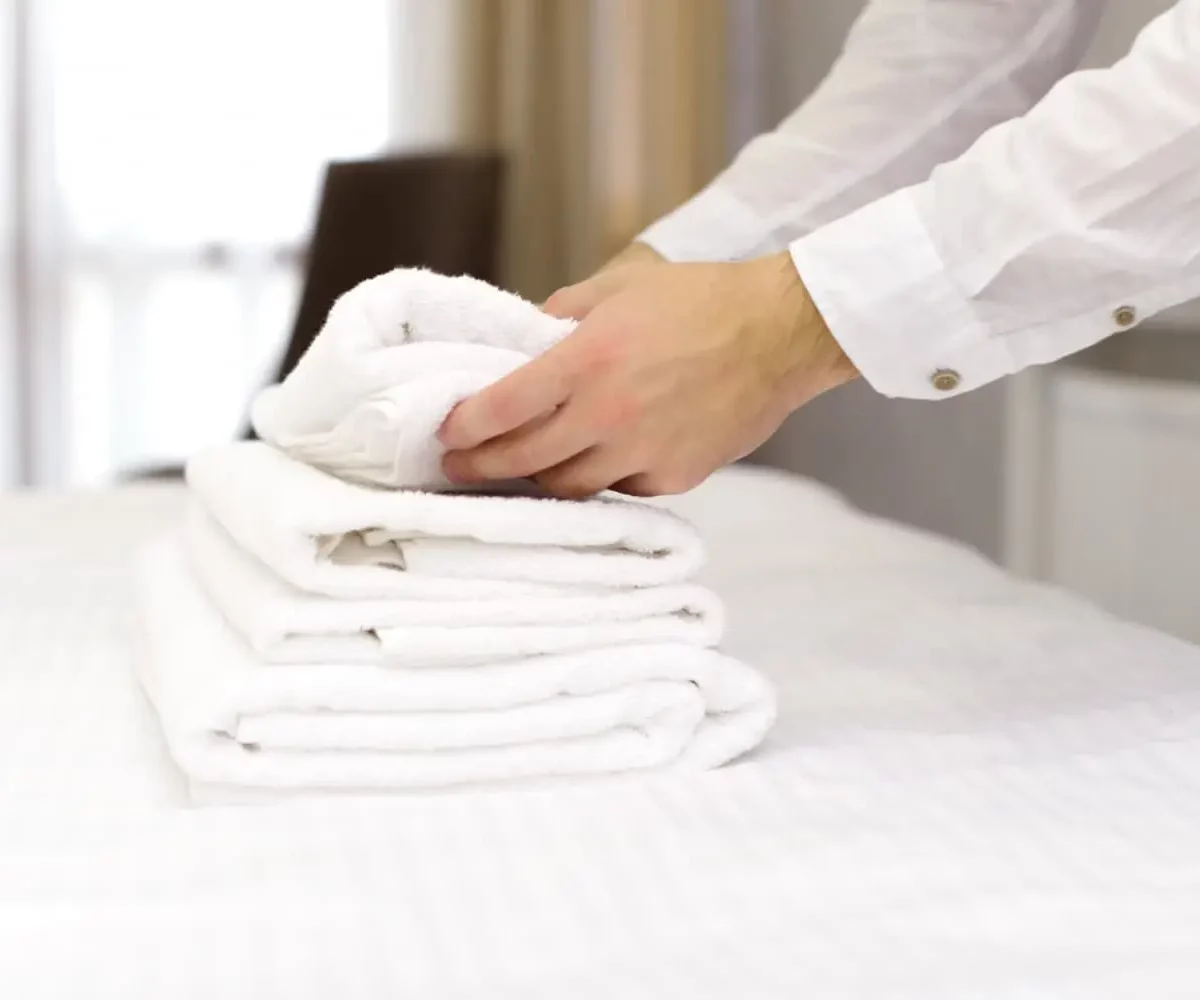 Frisch gefaltete Handtücher auf dem Hotelbett nach der Zimmerreinigung durch den Reinigungsdienst