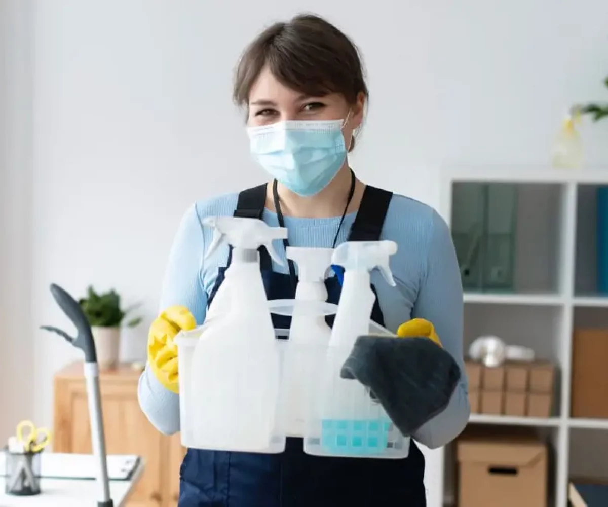 Reinigungskraft mit Mundschutz und Reinigungsmitteln für die Arztpraxisreinigung