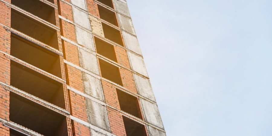 Unfertiger Rohbau mit offenen Fensterflächen und Backsteinfassade zum Thema Bauendreinigung vs Zwischenreinigung.