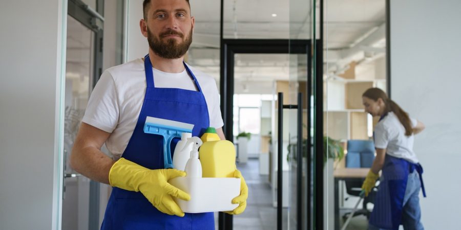 Reinigungskraft mit Reinigungsmitteln in einem Büro, passend zum Thema Gebäudereinigung Kosten.