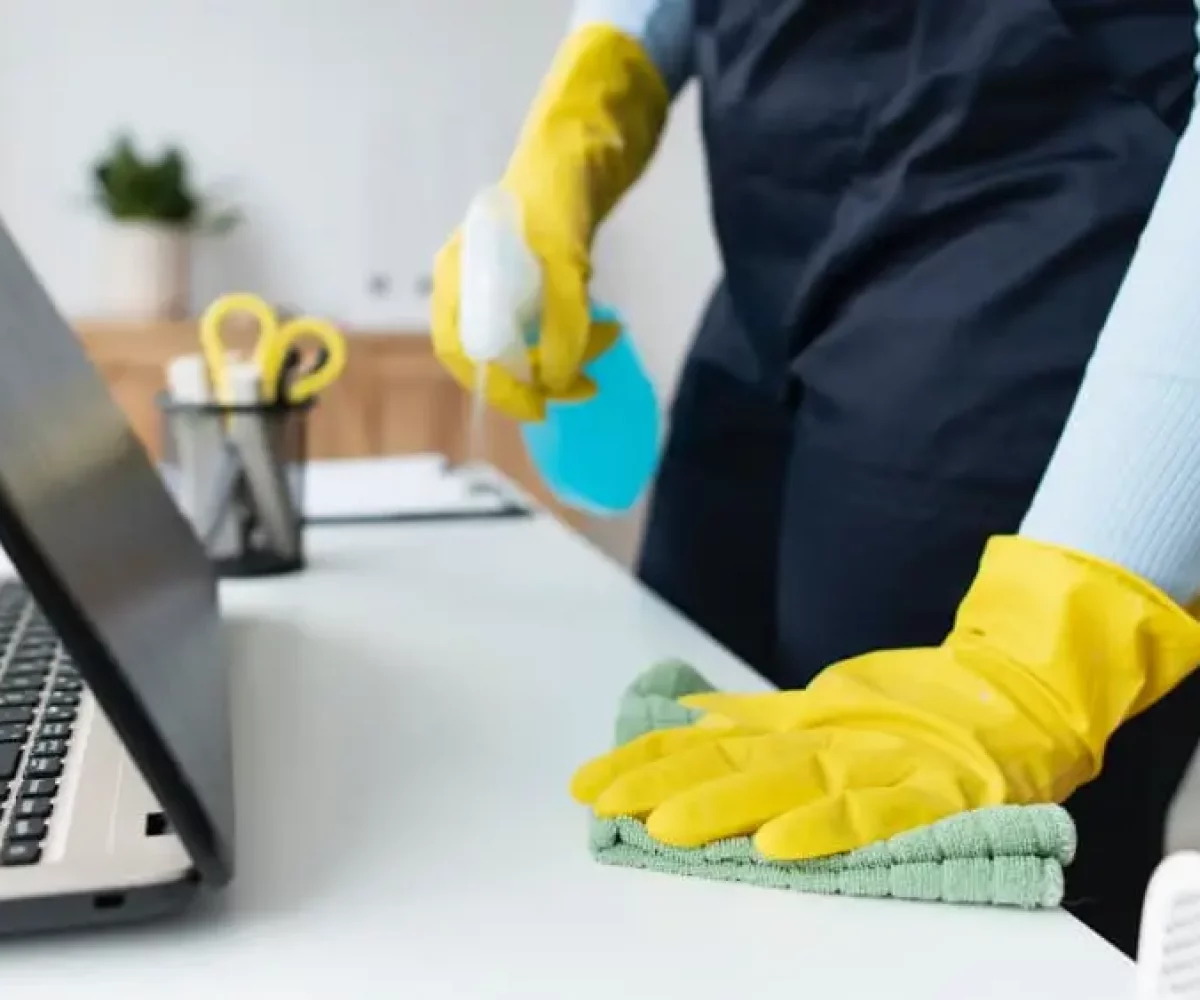Schreibtisch mit Laptop wird abgewischt, Büroreinigung für Büros und KMU