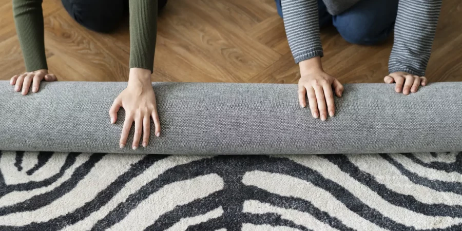 Gemusterter Teppich wird ausgerollt, Teppichreinigung gegen Textilmotten