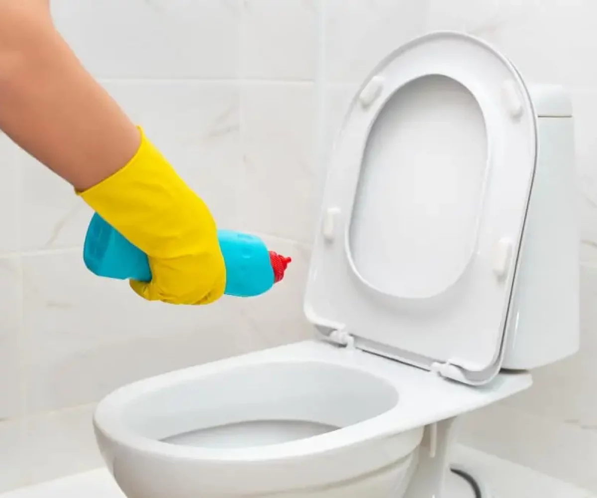Toilette wird mit Schutzhandschuhen geputzt, Sanitärreinigung im Gebäude