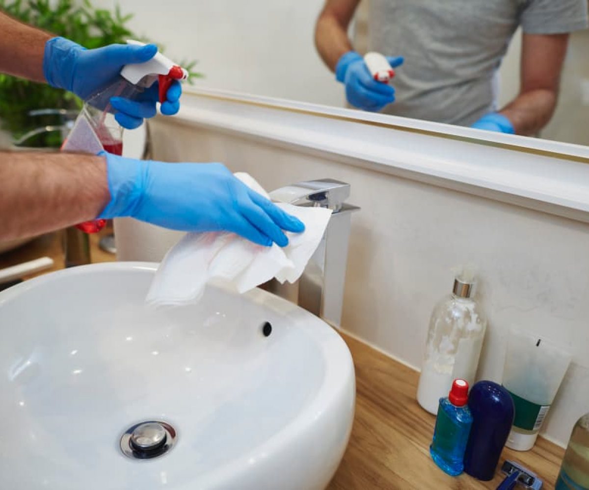 Sanitärreinigung am Waschbecken mit Reinigungsmittel und Tuch zur gründlichen Reinigung im Bad